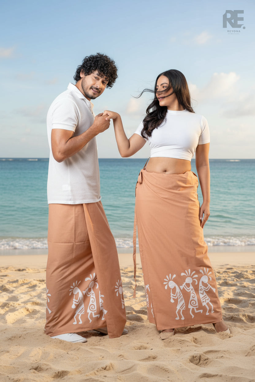 Man and woman wearing matching terracotta hand-painted batik unisex sarongs with white tribal motifs, from Reyona Clothing – RE-0087
