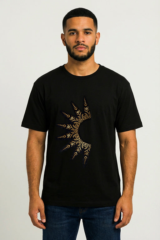 Male model wearing a black oversized unisex graphic T-shirt featuring a gold ornamental design by REYONA