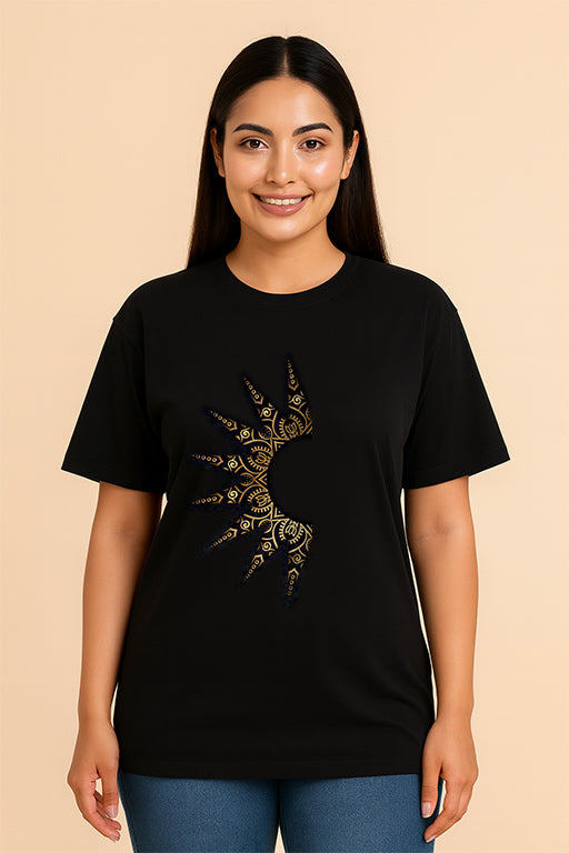 Female model wearing a black oversized unisex T-shirt with a gold abstract graphic design by REYONA